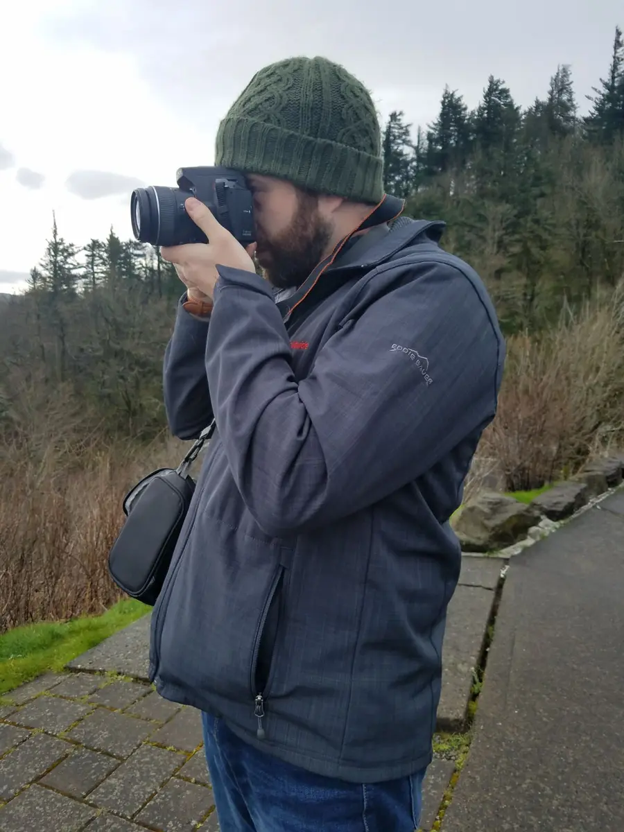 Dan Mints photographing outdoors, camera raised to his eye