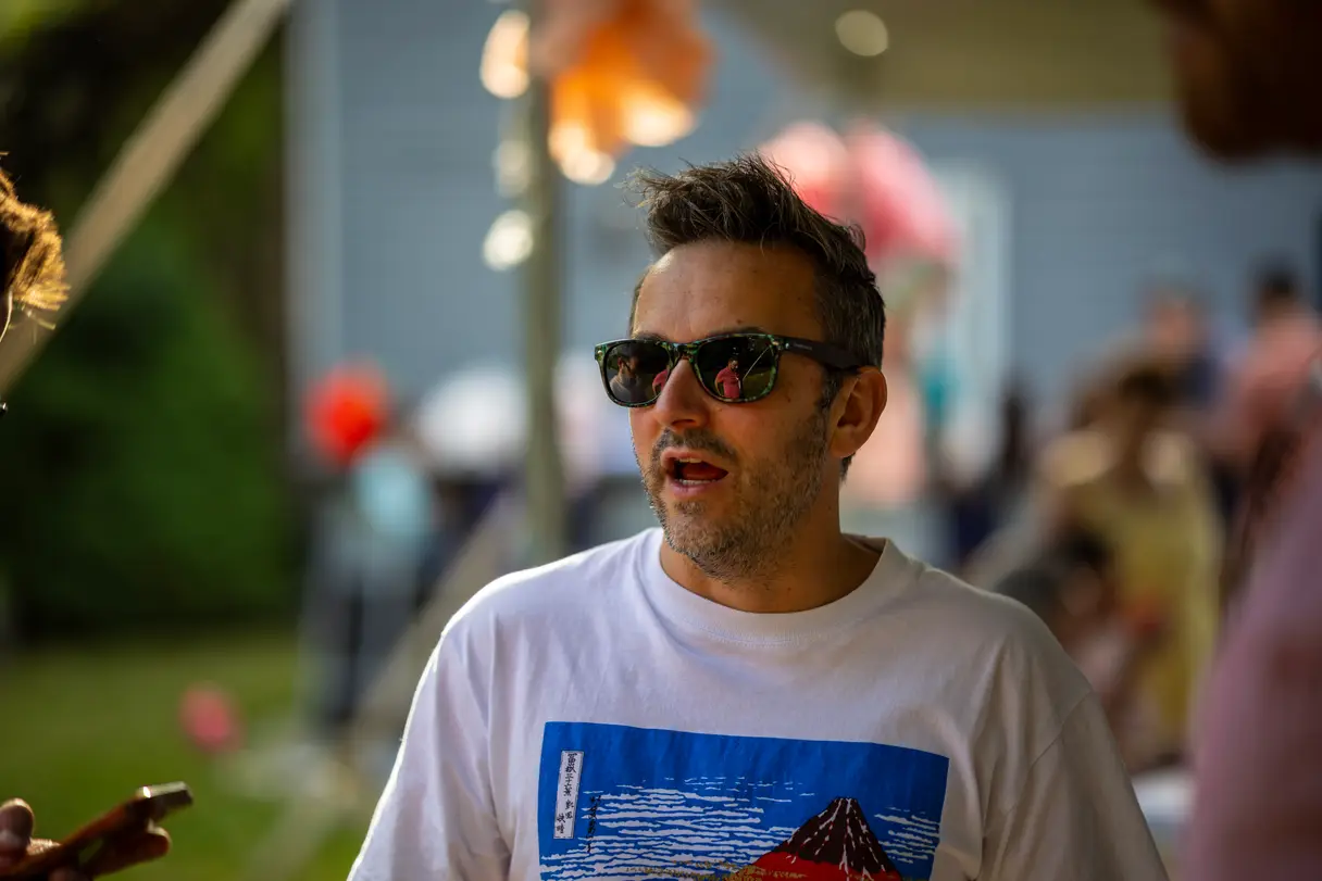 Man in sunglasses deep in conversation at a birthday party.