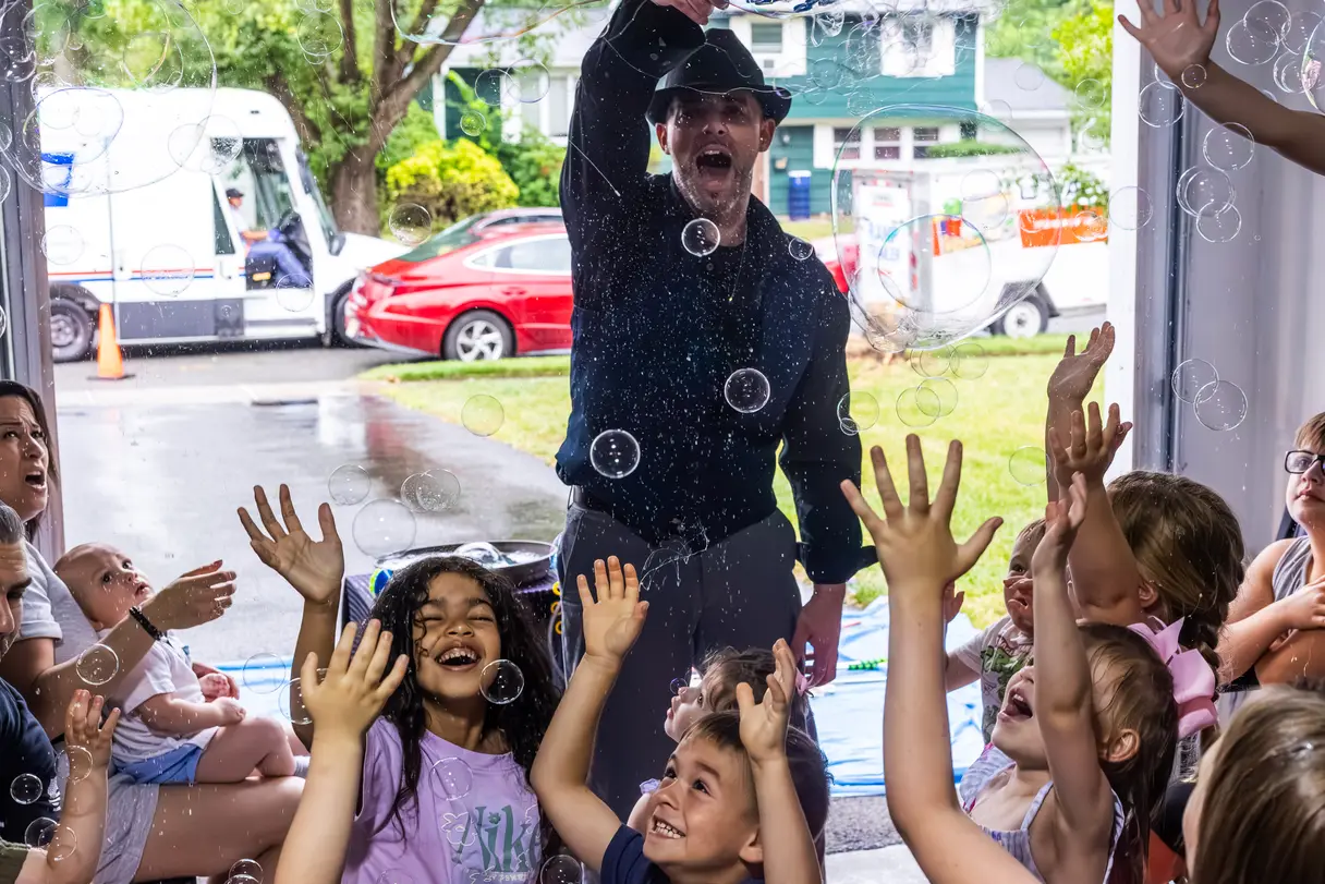 A magician performing a bubble show while kids laugh and squeal in delight.
