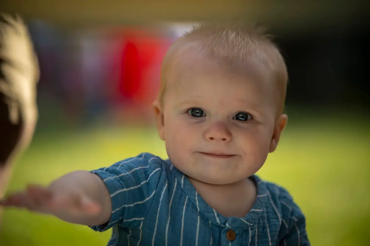Baby reaching out toward the camera with a beautifully blurred background.